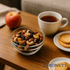 Ρεαλιστική φωτογραφία Fit Mix Μαύρη Σοκολάτα της EURONUTS σε μπολ, πάνω σε τραπέζι κουζίνας με καφέ και σνακ, φυσικό καθημερινό σκηνικό στο σπίτι.