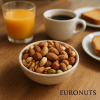 Ρεαλιστική φωτογραφία Fit Mix Ωμοί Ξηροί Καρποί EURONUTS σε μπολ πάνω σε ξύλινο τραπέζι, με φυσικό φωτισμό και συνοδευτικά ροφήματα, ιδανικό για καθημερινή κατανάλωση στο σπίτι.
